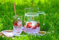 A jug and a glass of iced lemonade on a sunny lawn