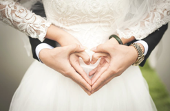Bride and groom holding hands together in the shape of a heart