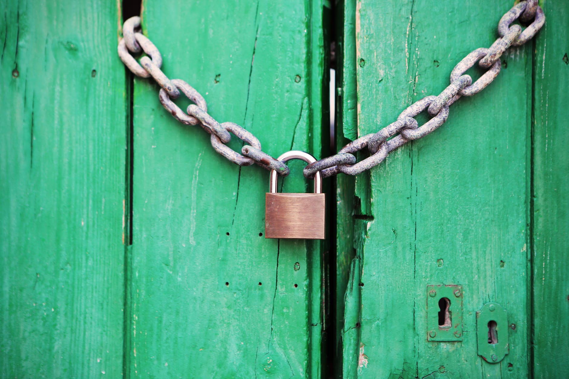 a chain and padlock holding green doors locked