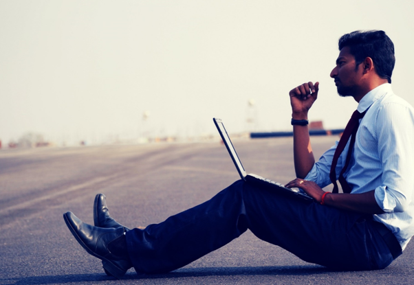 A man sitting down with his laptop and thinking