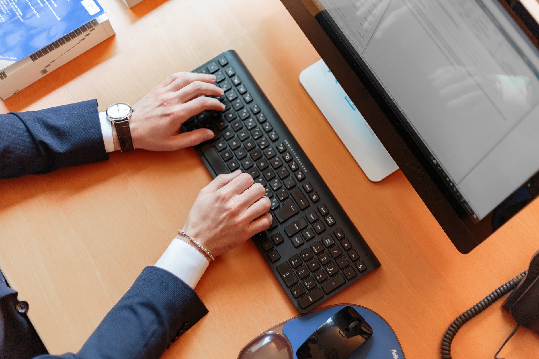 A person wearing a suit doing research on a laptop