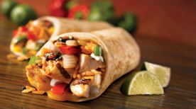 Two chicken fajitas with lime on a wooden surface
